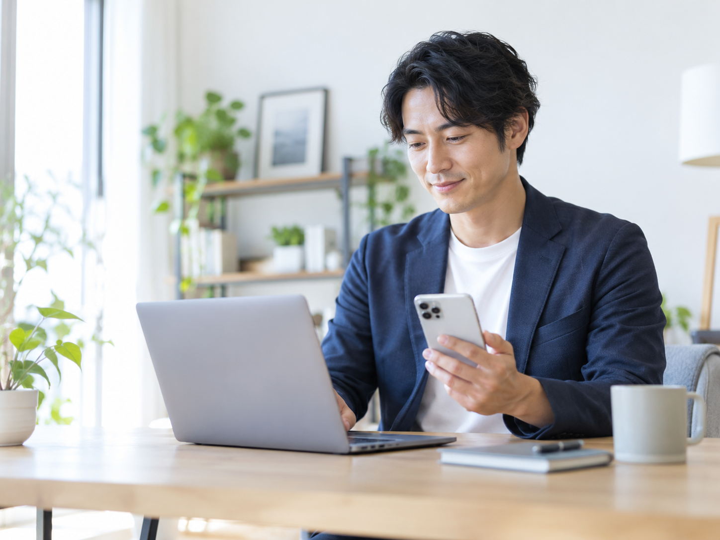 ノートパソコンとスマートフォンを使って仕事を効率化する様子